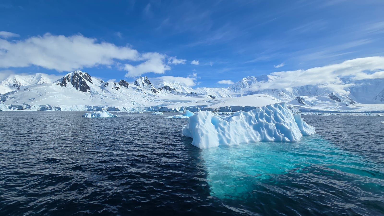 Iceberg com base turquesa diante das montanhas nevadas das Ilhas Shetland do Sul